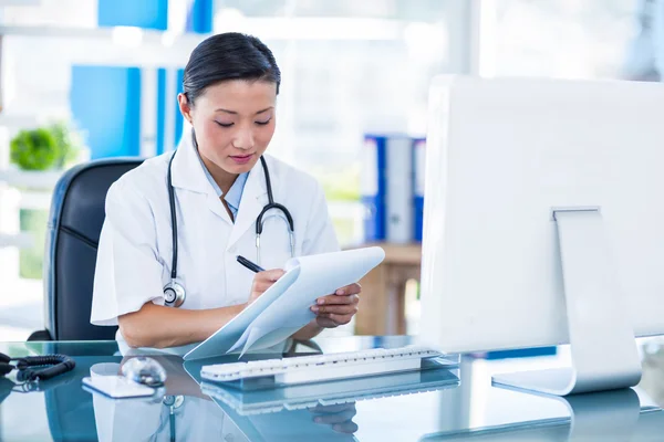 Médico concentrado escribiendo en portapapeles — Foto de Stock