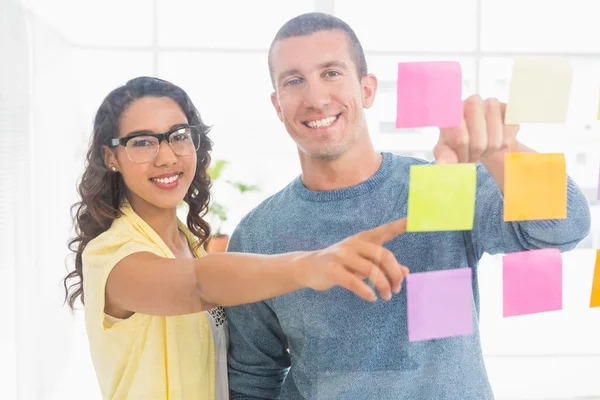 Portrait of smiling coworkers pointing sticky notes and looking — Stock Photo, Image