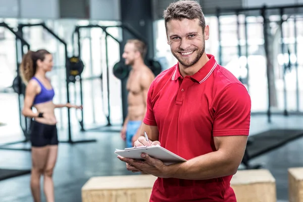 Muscular trainer writing on clipboard — Stock Photo, Image