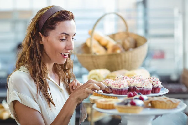 Pretty brunette choosing cupcake — Stock Photo, Image