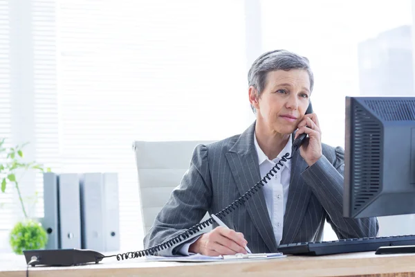 Lächelnde Geschäftsfrau telefoniert und schreibt — Stockfoto