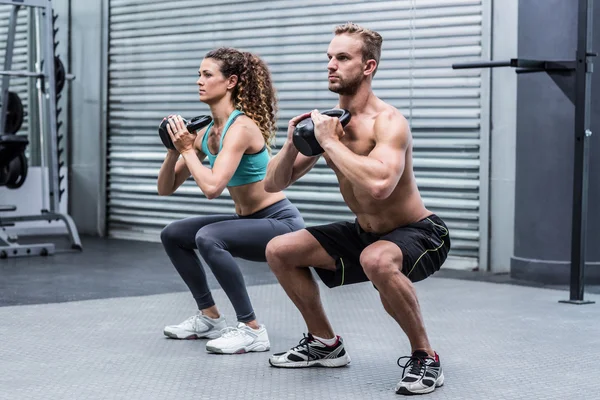 Muscular couple exercising with kettlebells — Stock Photo, Image
