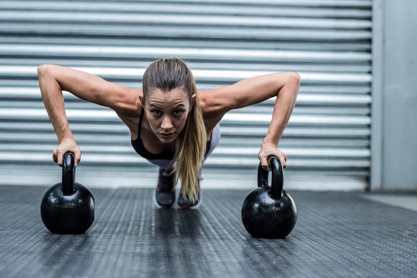 Mulher fazendo flexões com kettlebells — Fotografia de Stock