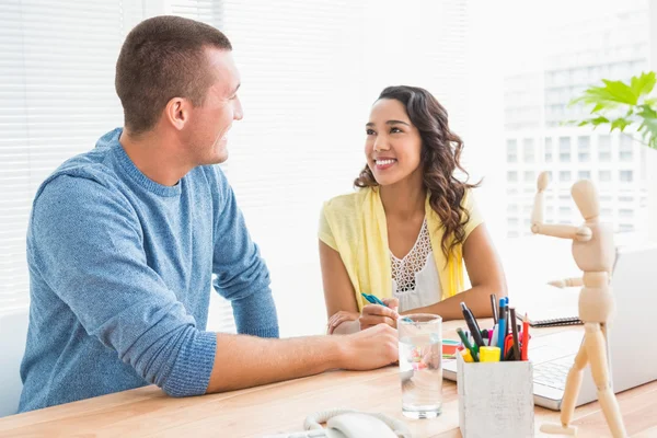 Smiling colleagues speaking at desk — Stock Photo, Image