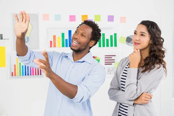 Jóvenes creativos de negocios mirando y mostrando algo en — Foto de Stock