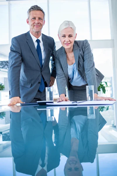 Business people looking at camera behind desk — Stock Photo, Image