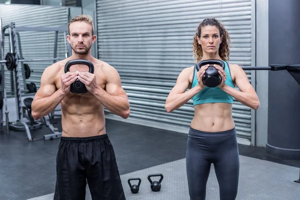 Muskulöses Paar, das mit Kettlebells trainiert — Stockfoto