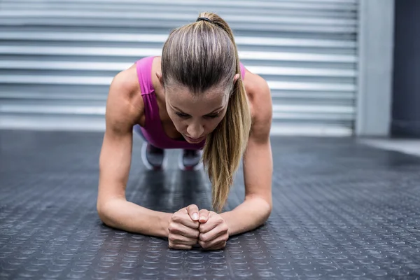 Een gespierde vrouw op een plank positie — Stockfoto