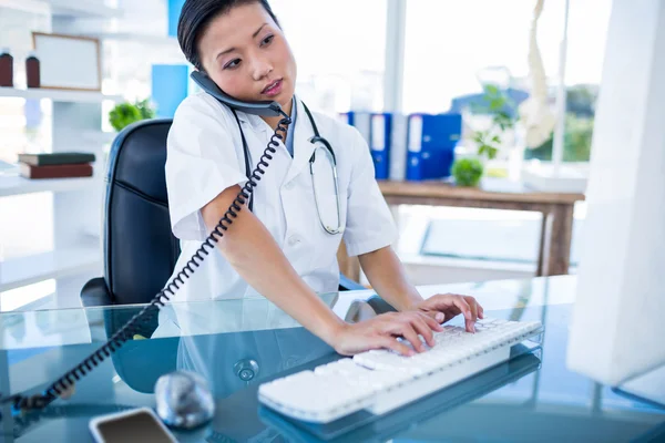 Médecin ayant un appel téléphonique et utilisant son ordinateur — Photo