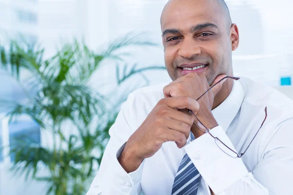 Homme d'affaires souriant tenant des lunettes de lecture — Photo