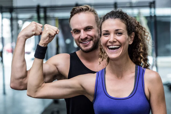 Glimlachend gespierde paar buigen biceps — Stockfoto