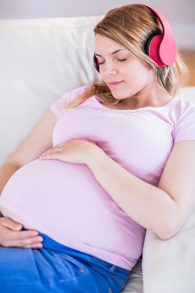 妊娠中の女性は、音楽を聴く — ストック写真