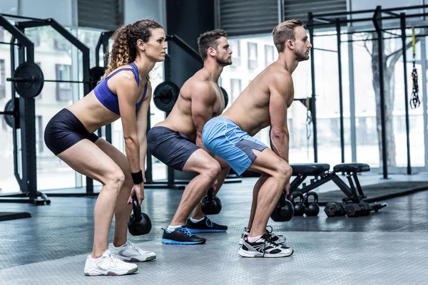 Atletas musculares agachamento com kettlebells — Fotografia de Stock