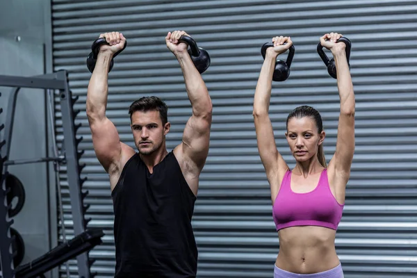 Um casal muscular levantando kettlebells — Fotografia de Stock