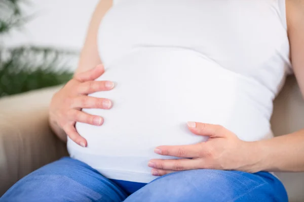 Zbliżenie kobiety w ciąży z dłońmi na brzuchu — Zdjęcie stockowe