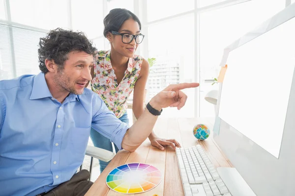 Casual businesswoman looking at colleagues computer — Stockfoto