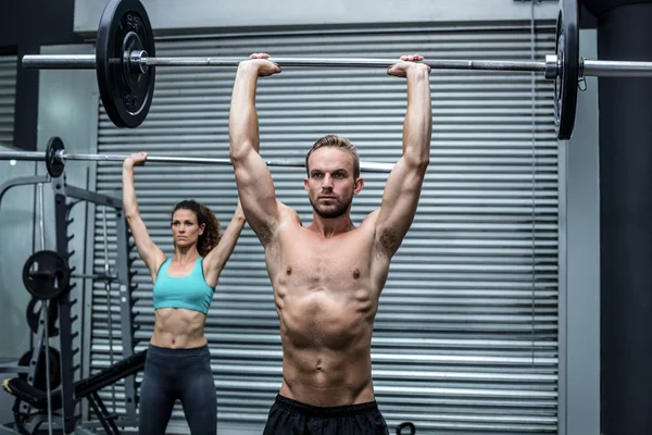 Muscular couple lifting weight together — Stock Photo, Image