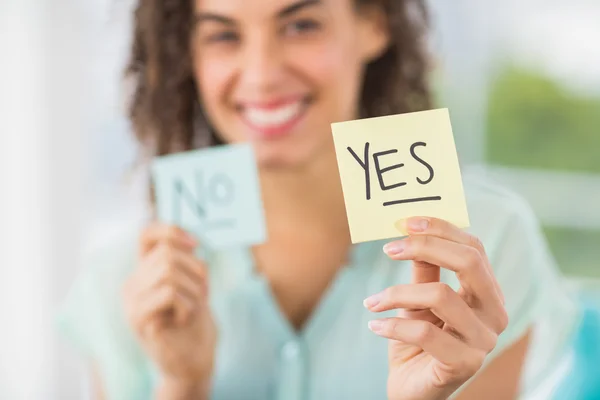 Smiling businesswoman holding yes and no sticks — Stock Photo, Image