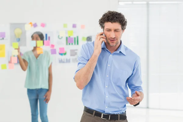 Businessman having phone call while his colleague posing — Stok fotoğraf