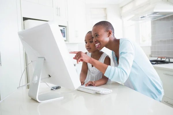 Glada leende mamma med sin dotter med hjälp av dator — Stockfoto