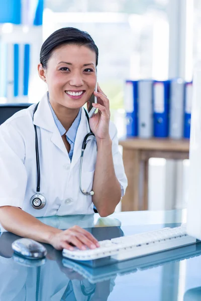 Médico sonriente mirando a la cámara y teniendo una llamada telefónica — Foto de Stock