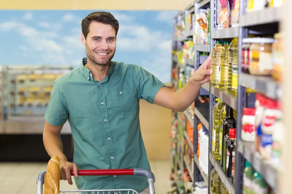 Portret van lachende man nemen olie in de winkelrekken van gangpad — Stockfoto
