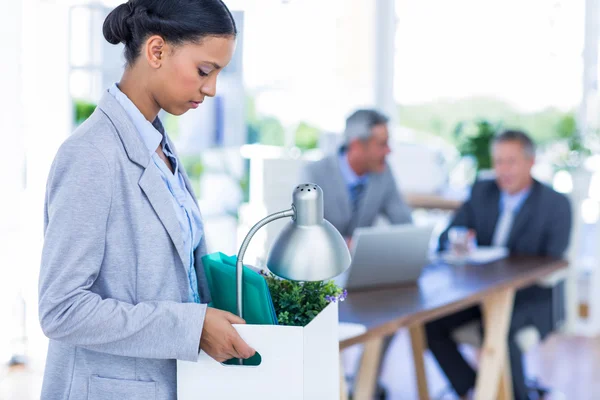 Businesswoman holding box with her colleagues behind her — Stock Photo, Image