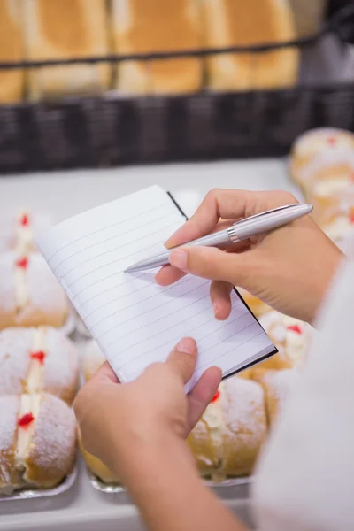 Uma mulher tomando notas acima de doces — Fotografia de Stock