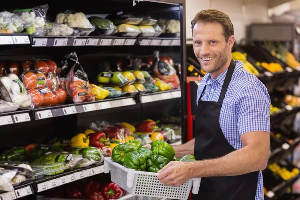 Retrato de un trabajador guapo sonriente sosteniendo una caja con vegetab — Foto de Stock