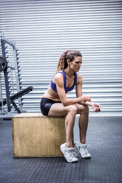 Fokussierte muskulöse Frau sitzt auf einer Kiste — Stockfoto