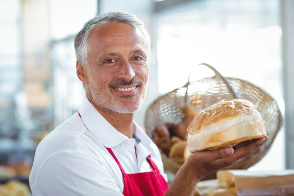 Kellner blickt in Kamera und hält frisch gebackenes Brot in der Hand — Stockfoto