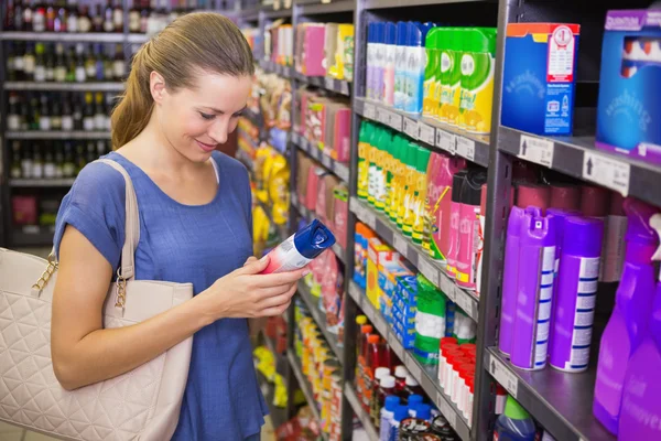 Przemyślane ładna brunetka patrząc na produkt w półce — Zdjęcie stockowe