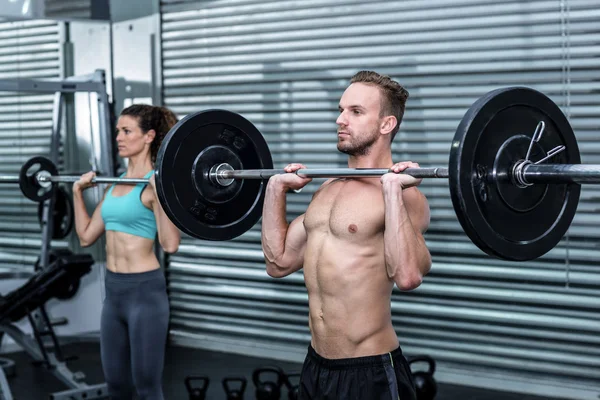 Muscular couple lifting weight together — Stock Photo, Image