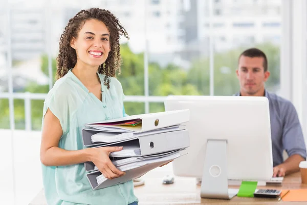 Glimlachende zakenvrouw die een stack van mappen — Stockfoto