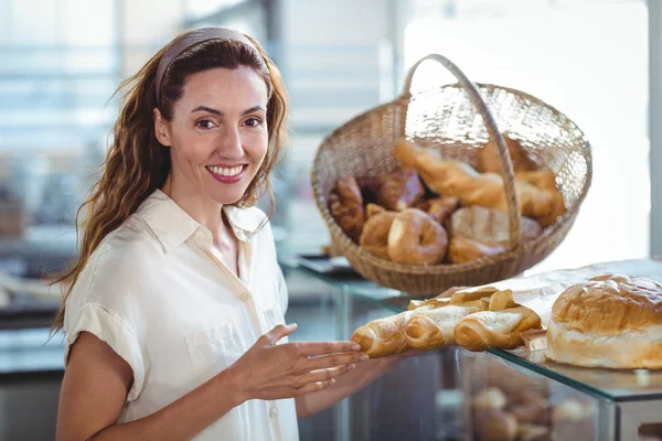 Bonita morena sonriendo a la cámara y sosteniendo pan —  Fotos de Stock