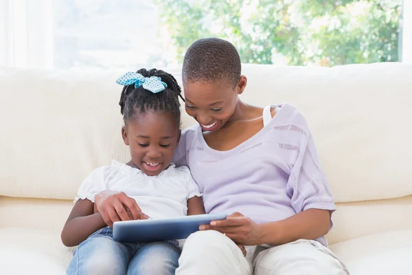 Mutlu gülümseyen anne kızıyla kanepede birlikte tablet kullanma — Stok fotoğraf