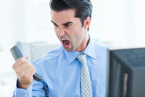 Geschäftsmann schreit, als er im Büro sein Telefon hinhält — Stockfoto