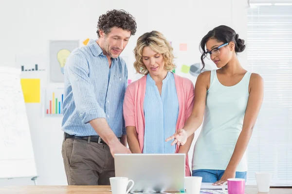 Casual Business Team schaut gemeinsam auf Laptop — Stockfoto