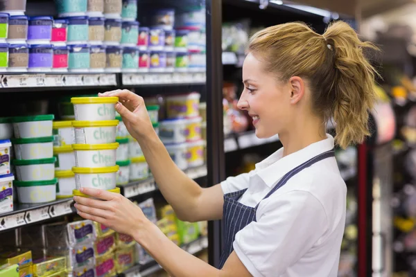 Smiling blonde worker taking a products in shelf Stock Picture