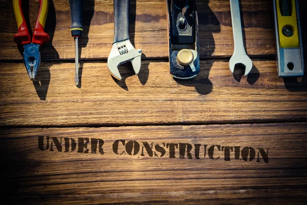Em construção contra mesa com ferramentas — Fotografia de Stock