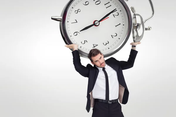 Businessman in suit lifting up alarm clock — Stock Photo, Image