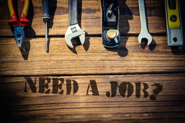 Precisa de um emprego? contra mesa com ferramentas — Fotografia de Stock