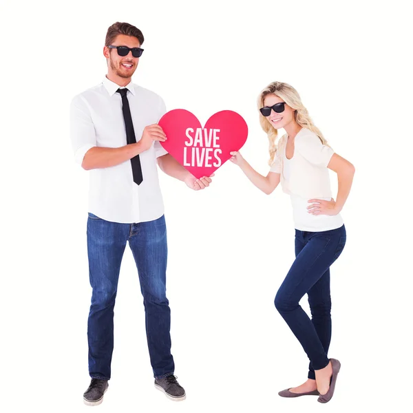 Composite image of cool young couple holding red heart — Stock Photo, Image