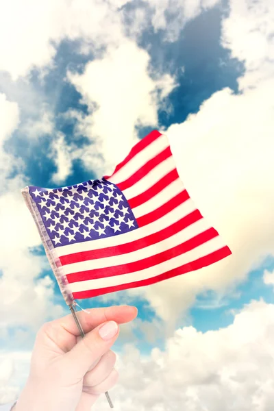 Imagen compuesta de la mano ondeando bandera americana — Foto de Stock