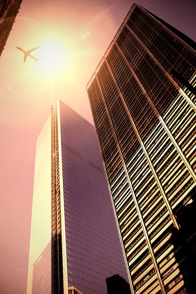 Airplane flying over buildings — Stock Photo, Image