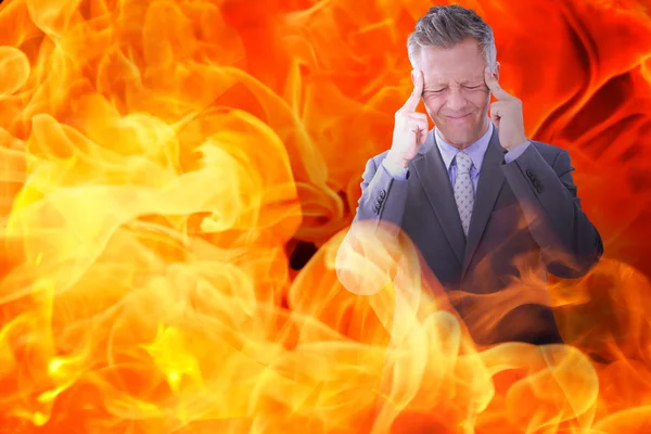 Businessman with headache against fire — Stock Photo, Image