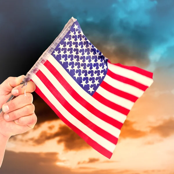 Zusammengesetztes Bild der Hand, die die amerikanische Flagge schwenkt — Stockfoto