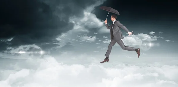 Geschäftsmann springt und hält Regenschirm — Stockfoto