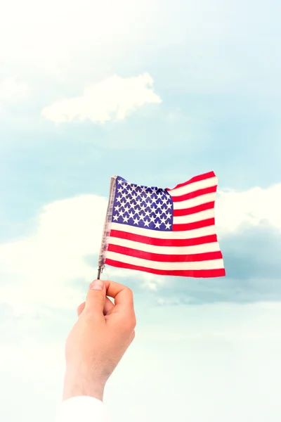 Imagen compuesta de la mano ondeando bandera americana — Foto de Stock