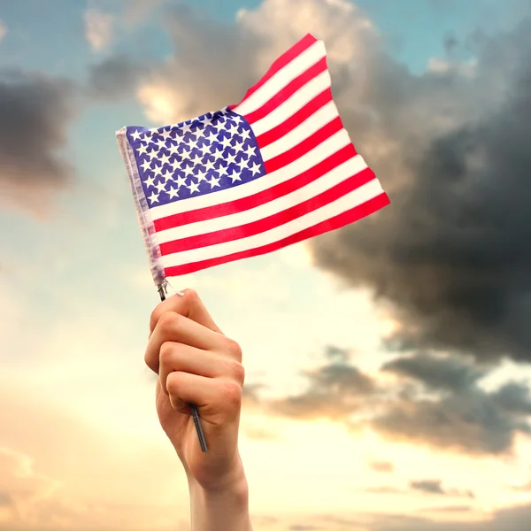 Imagen compuesta de la mano ondeando bandera americana — Foto de Stock